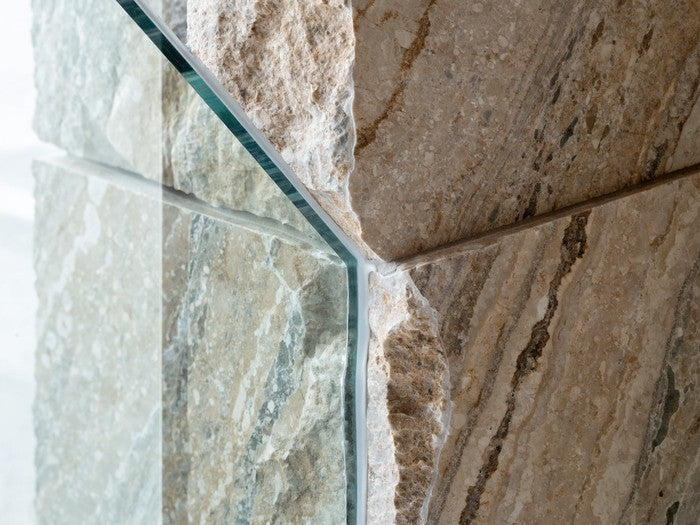 AI shot reference standing in for photography. A bathroom. Frameless glass shower door meeting tile, the cured bead clear and glossy.
