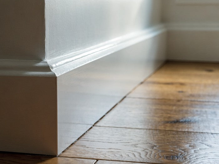 AI shot reference standing in for photography. A real room. Baseboard meeting drywall, white bead tooled and not yet painted.