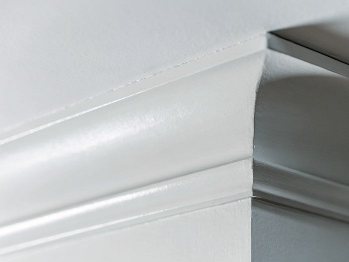 AI shot reference standing in for photography. Interior. Crown molding or window casing after the coat, the caulked joint painted over.