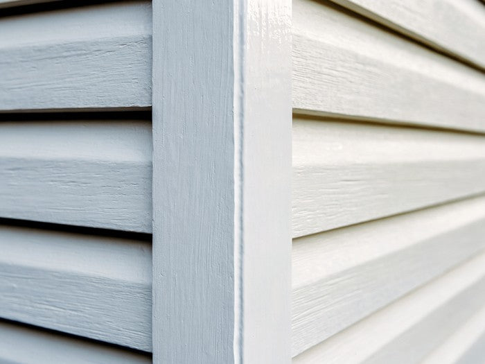 AI shot reference standing in for photography. Exterior, daylight. Siding or exterior trim joint with the white bead run.
